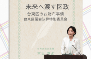 台東区議会議員の本目さよが、決算特別委員会で財政運営について質問している様子。
画像上部には「未来へ渡す区政　台東区のお財布事情　台東区議会決算特別委員会」と書かれている。